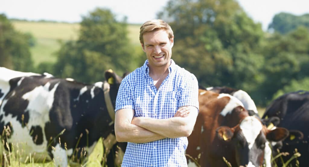 Bewital agri Landwirt auf der Weide mit einer Kuhherde im Hintergrund